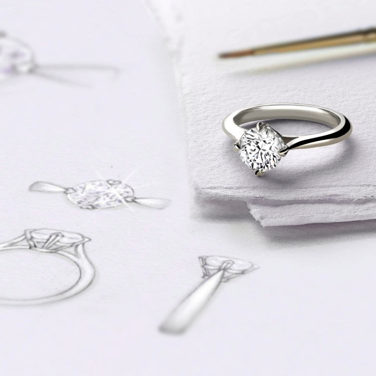 Bespoke engagement ring displayed alongside original hand-drawn design sketches