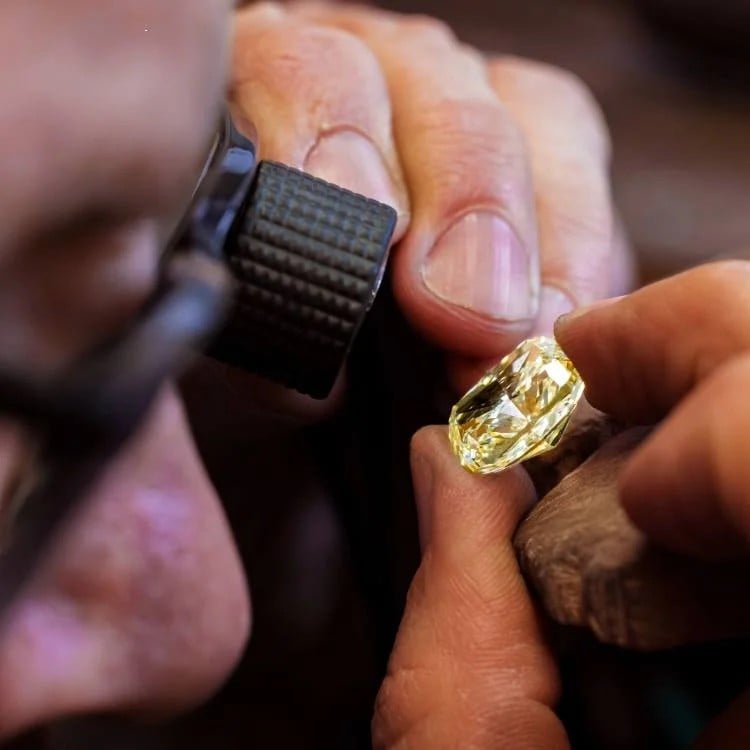 Jeweller examining a yellow gemstone in the Pragnell workshop