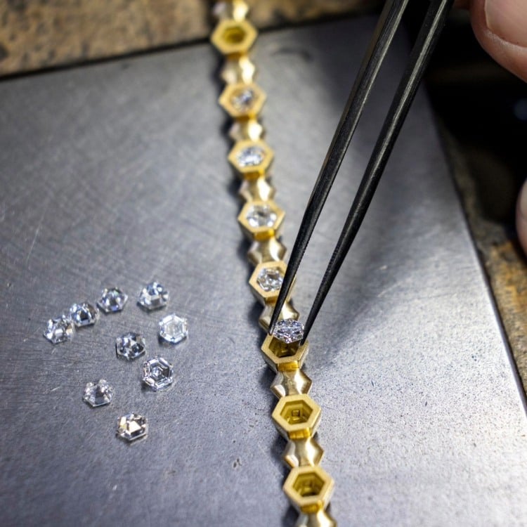Close-up of diamonds being set into a gold tennis bracelet during jewellery making
